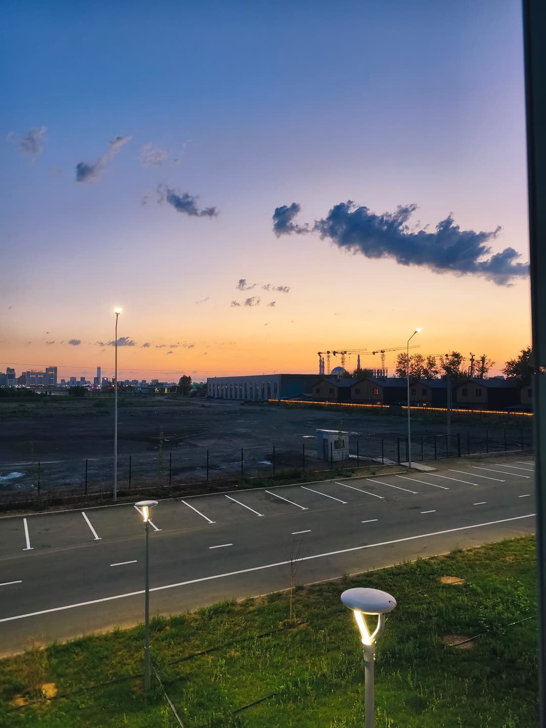 Sunrise over an empty parking lot with the distant Astana skyline on the horizon