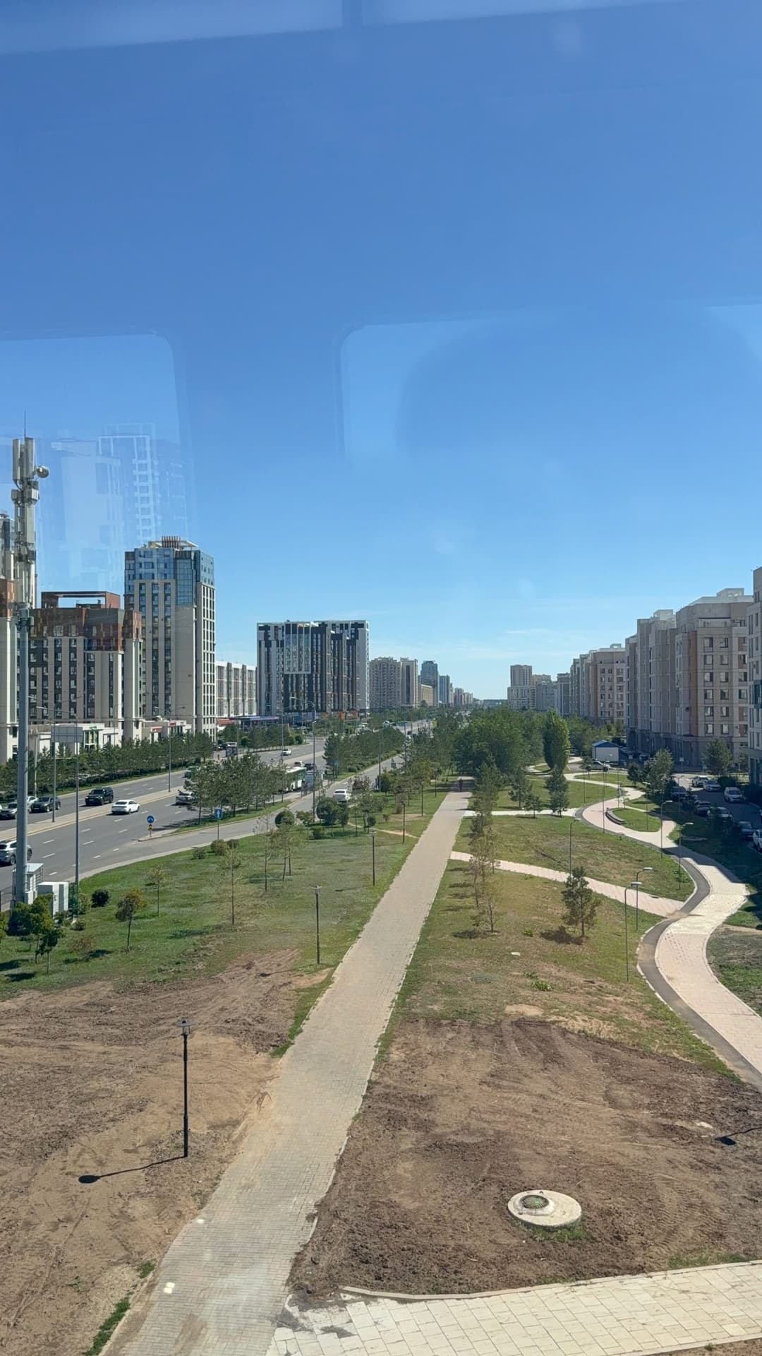 View from an elevated metro train of Astana's modern high-rise skyline and a long strip of green park below