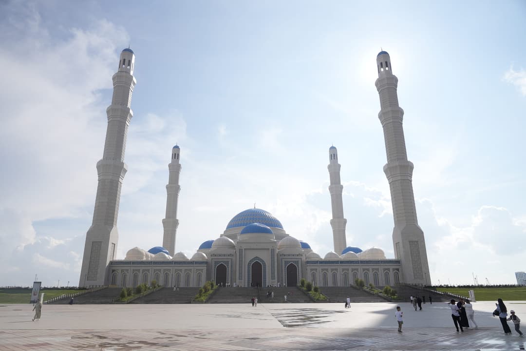 The Grand Mosque of Astana seen from the plaza, with a blue central dome and four tall white minarets
