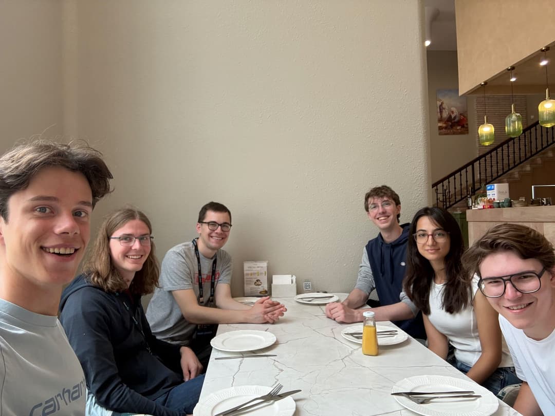 Team Germany sitting around a long white table in a small Astana restaurant, smiling at the camera