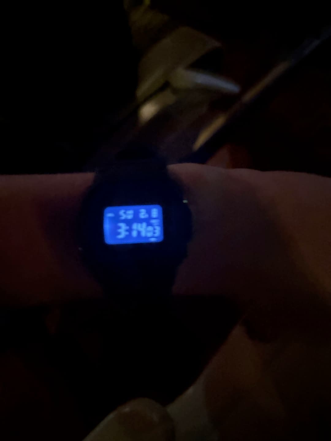 Close-up of a digital wristwatch showing an early morning time inside a dim shuttle bus